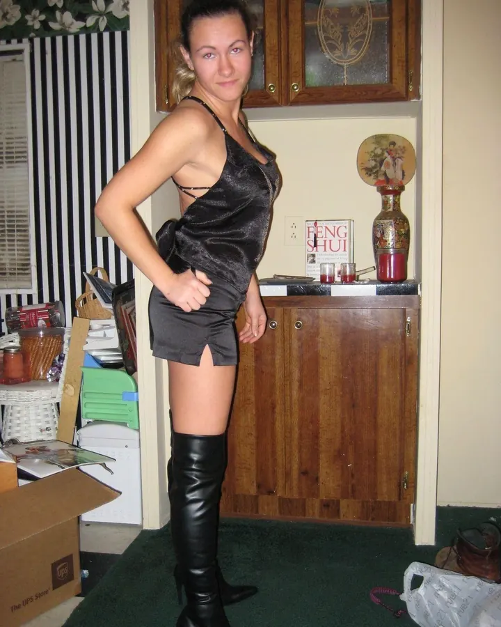 Femme trans aux cheveux bruns, prenant un selfie, portant un haut noir.